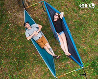 Two people laying side-by-side in hammocks kept separated by two multi-colored aluminum bars at their head and feet.