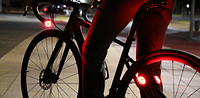 A bike with shining red, rear lights installed on it in a dark setting.