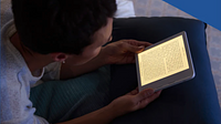 A guy reading on a white Kobo Libra 2 in bed.