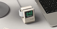 An Apple Watch nestled in a charger shaped like the original Macintosh.